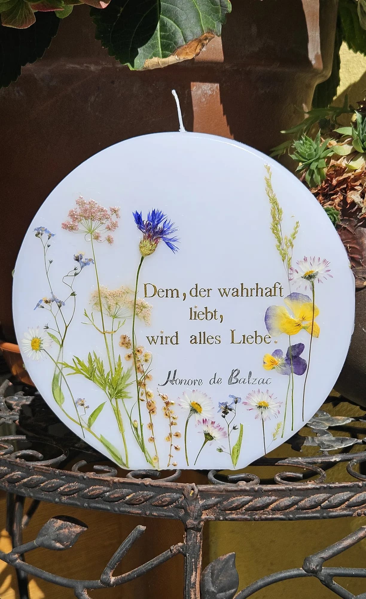 Runde Kerze mit gepressten Wiesenblumen und Spruch