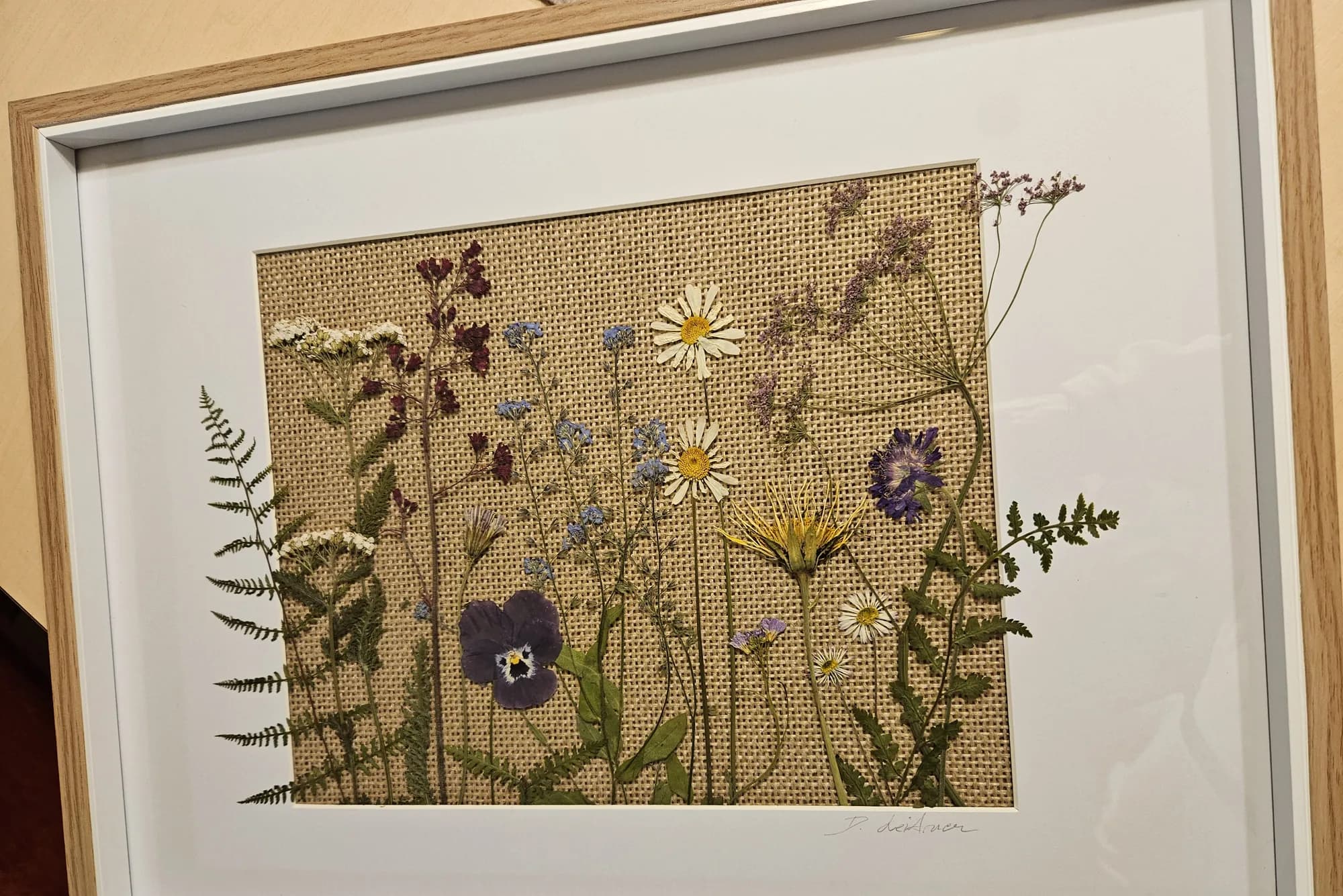 Gerahmtes Bild mit gepressten Wildblumen auf Jute, heller Holzrahmen