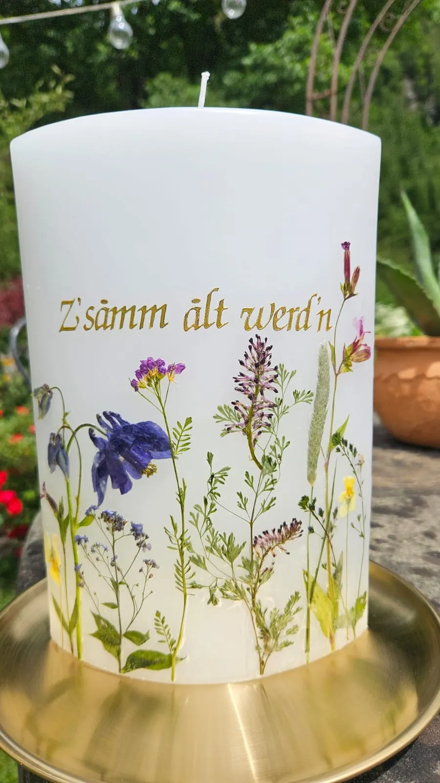 Kerze mit Mundart-Spruch in Gold und gepressten Wildblumen