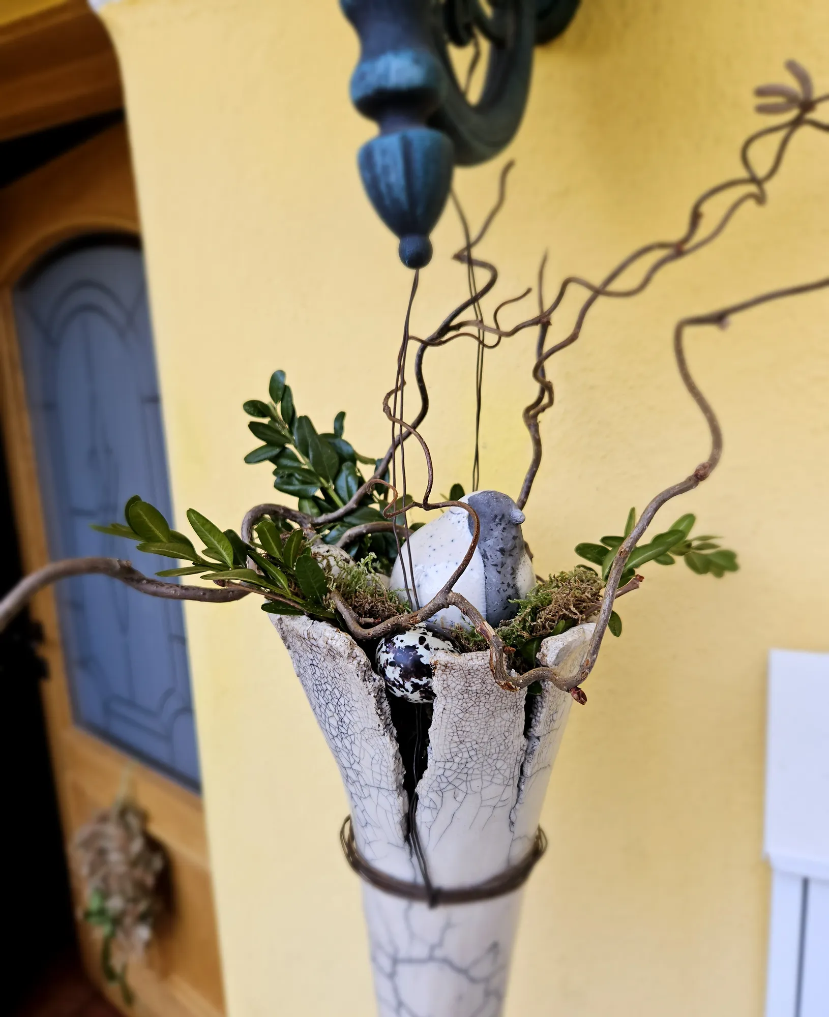 Weiße Hängevase aus Keramik mit Buchsgrün und gedrehten Zweigen