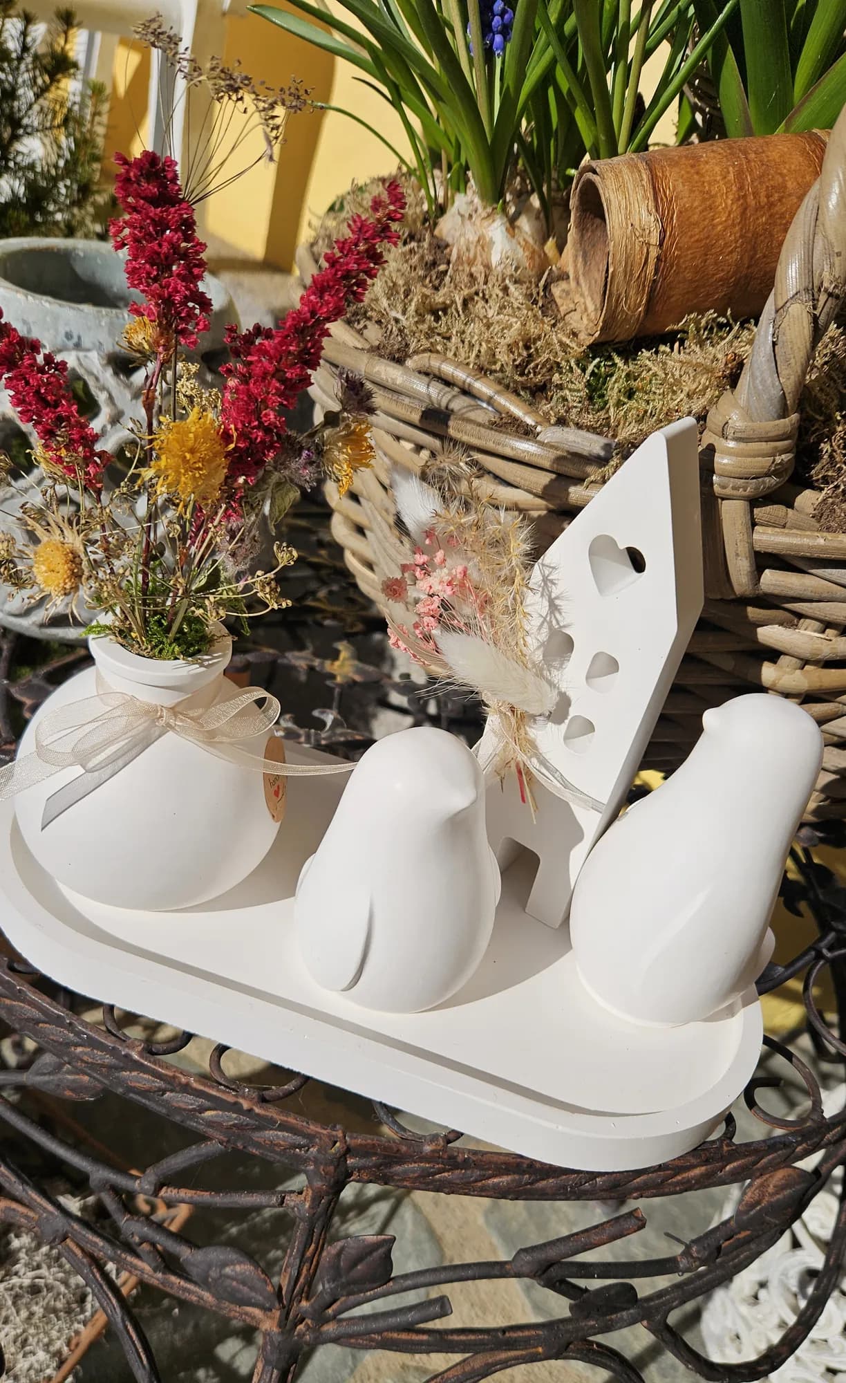 Weiße Keramiktauben auf einem Holztablett mit roten und rosa Trockenblumen