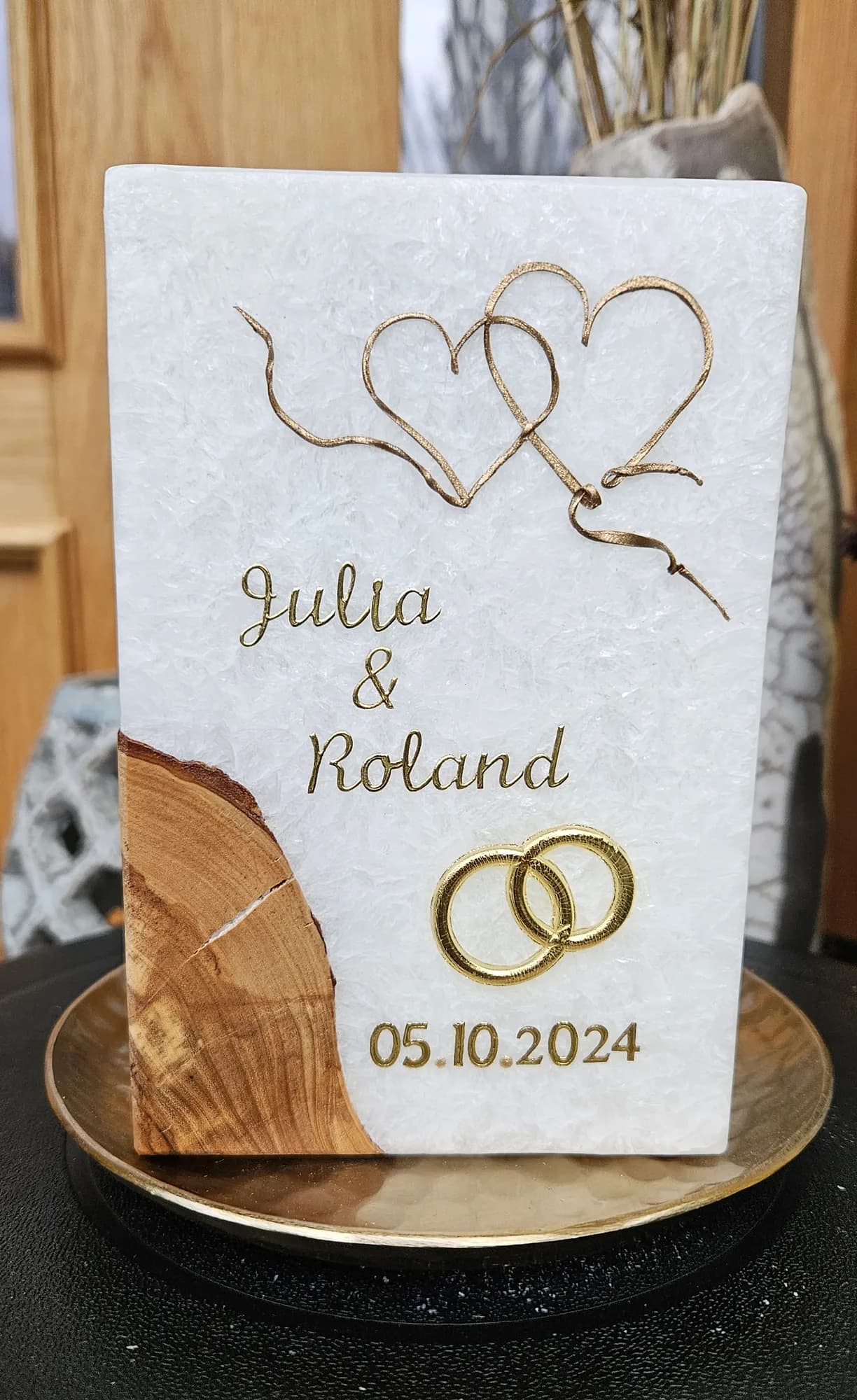 Weiße Hochzeitskerze mit zwei verschlungenen goldenen Herzen und Ringen