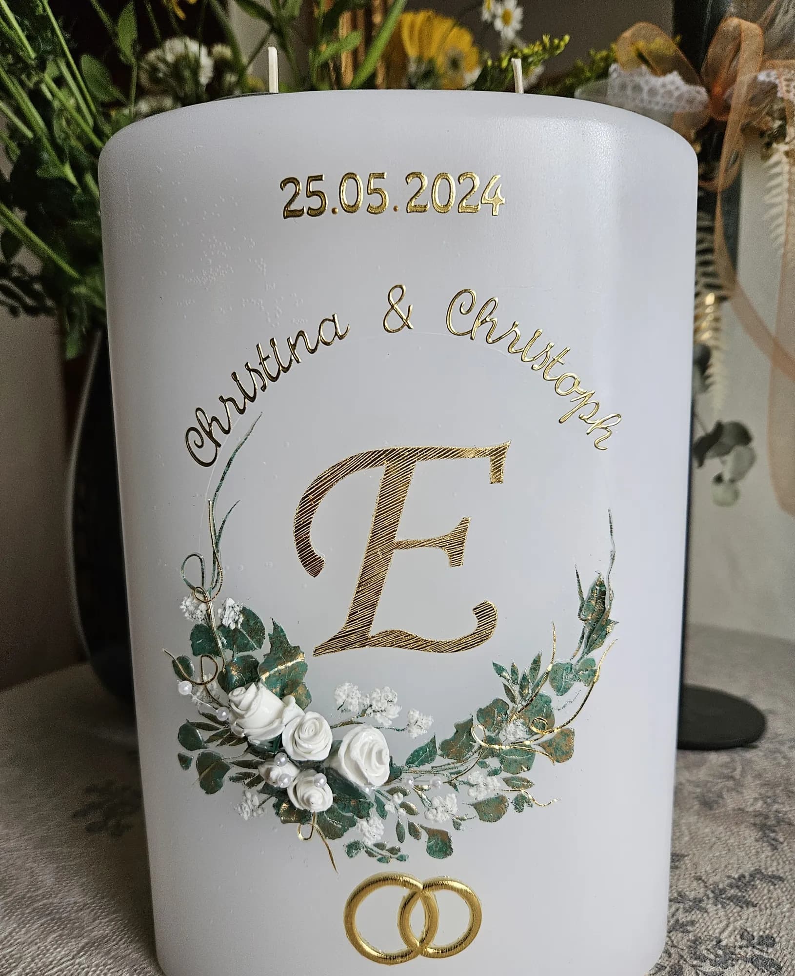 Weiße Hochzeitskerze mit goldenem Monogramm, Eukalyptuskranz, weißen Rosen und Trauringen
