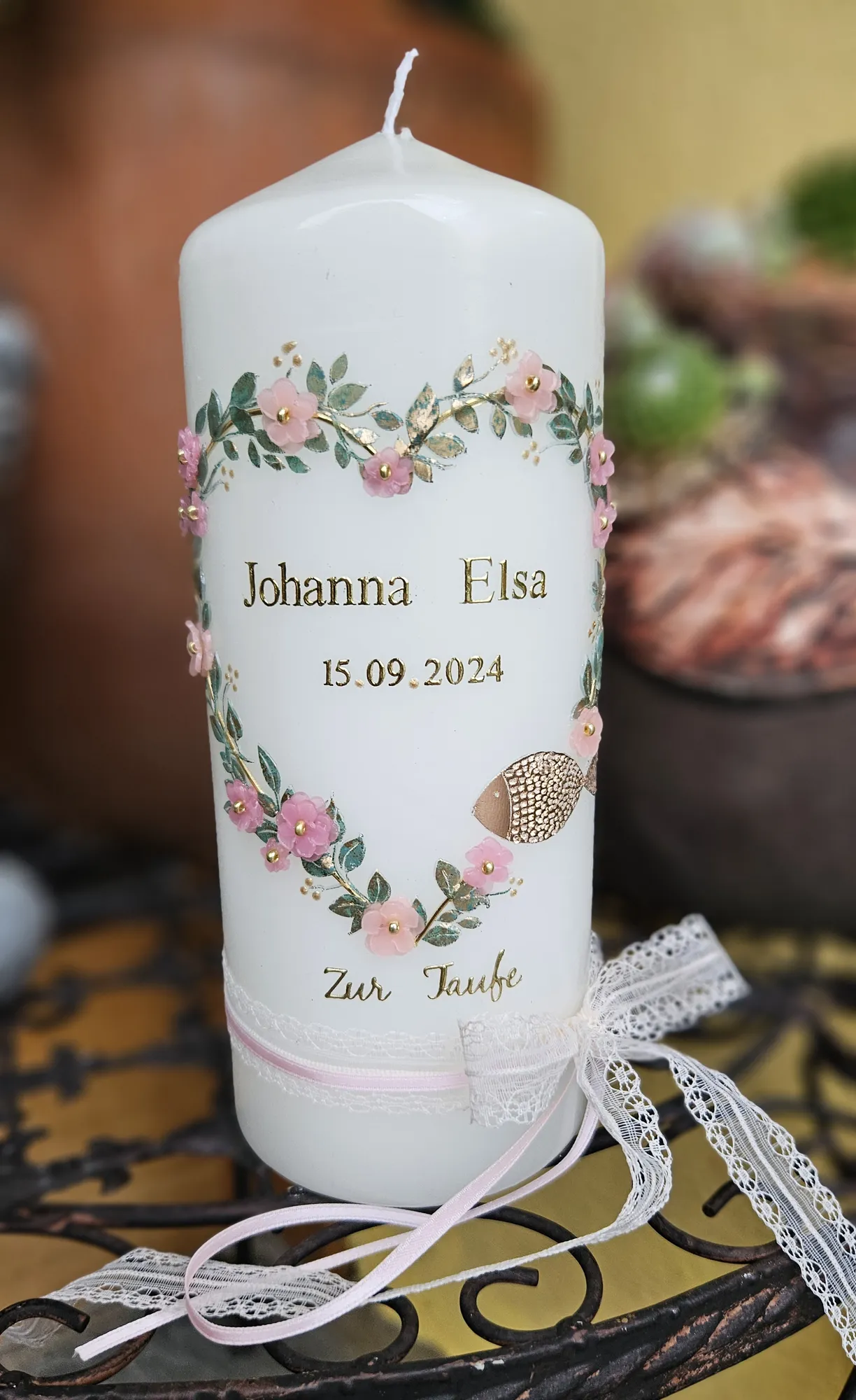 Weiße Taufkerze mit einem Herz aus rosa Blüten, Namen und Datum, mit Tüllschleife