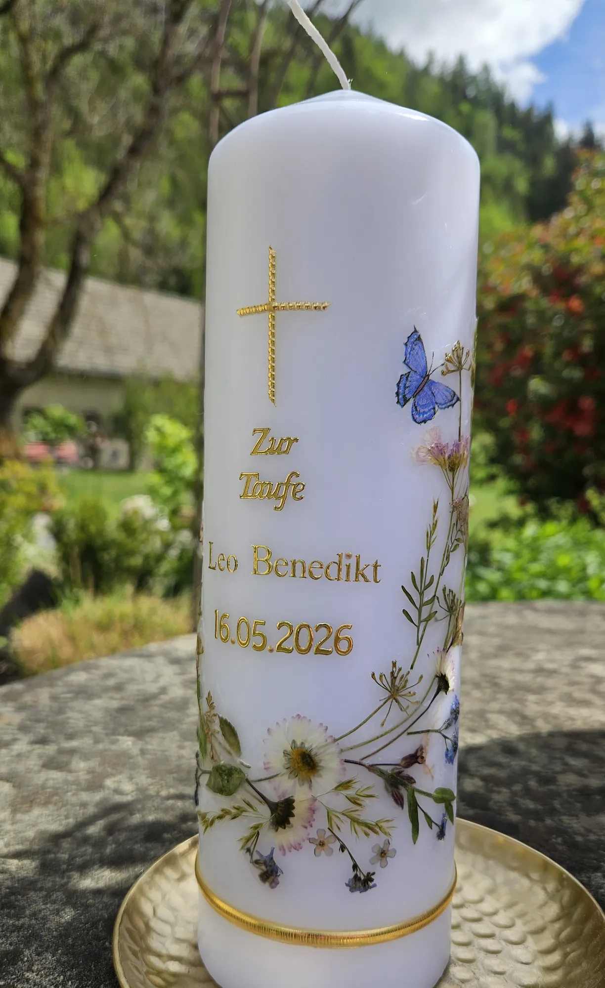 Weiße Taufkerze mit goldenem Kreuz, blauem Schmetterling und Wildblumen