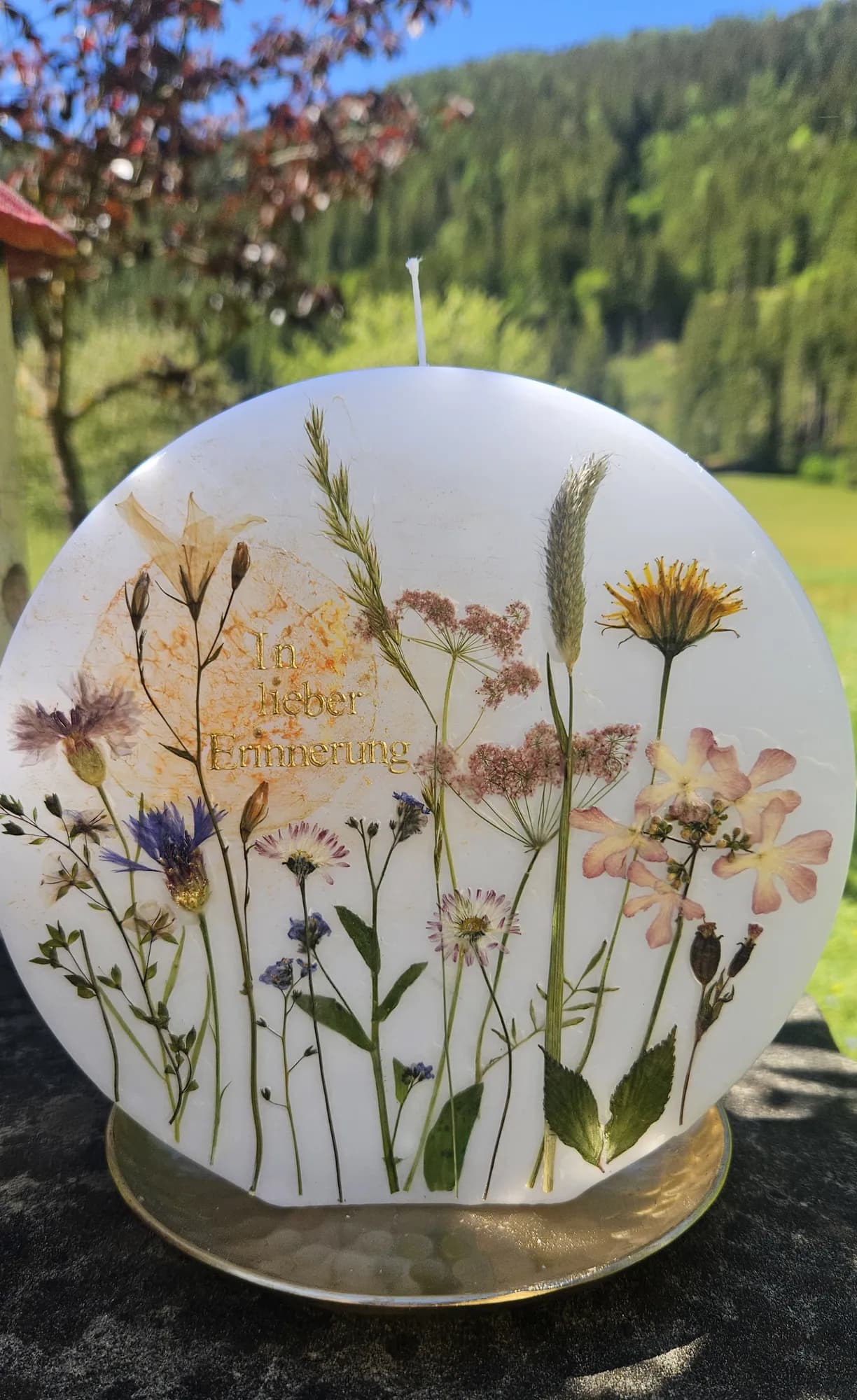 Runde Gedenkkerze mit gepressten Wiesenblumen und dem Schriftzug In lieber Erinnerung