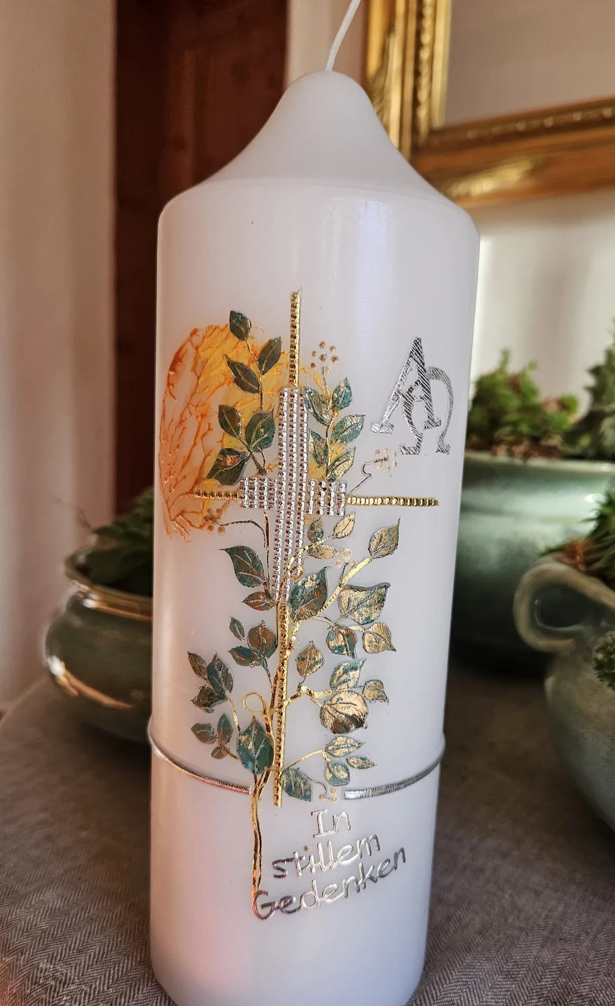 Weiße Trauerkerze mit herbstlichem Blätterzweig, Kreuz und Alpha und Omega